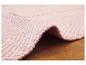 Un tapis rayé rose et blanc avec une texture grossièrement tissée.