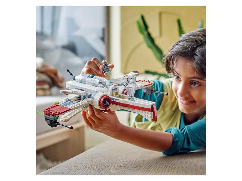 Garçon heureux joue avec un vaisseau spatial LEGO Star Wars blanc et rouge et une figurine.