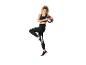 Femme en tenue de sport noire avec un anneau d'exercice, en équilibre sur une jambe.