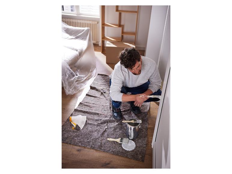 Un homme peint une porte avec de la peinture blanche et un pinceau.