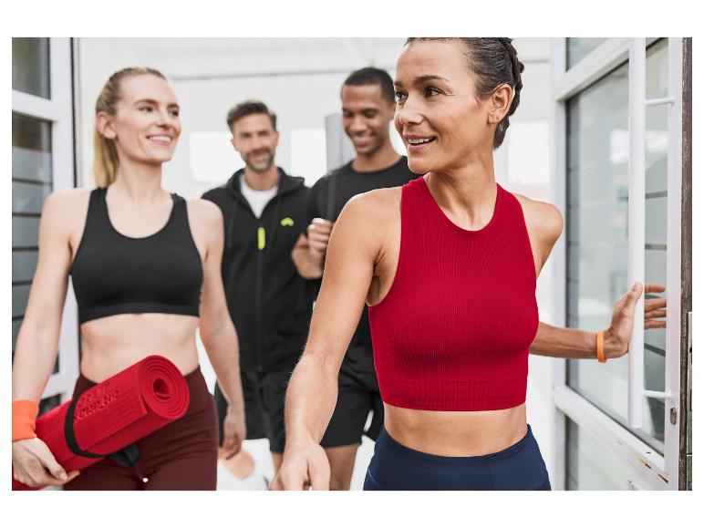 Jeunes femmes athlètes quittent une salle de sport avec des tapis de yoga.