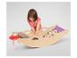 Une petite fille range des jouets dans un lit de poupée en bois.