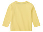 Un t-shirt jaune clair à manches longues pour bébé.