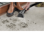Nettoyeur de tapis pulvérisant de l'eau sur un tapis sale avec des empreintes de boue.