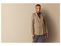Une femme en blazer beige et pantalon gris.