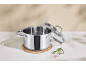 Casserole en acier inoxydable avec couvercle en verre et épices sur surface en marbre.