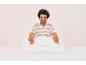 Un homme range des draps blancs sur un lit.