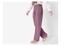 Femme marchant avec un pantalon large mauve et des sandales compensées.
