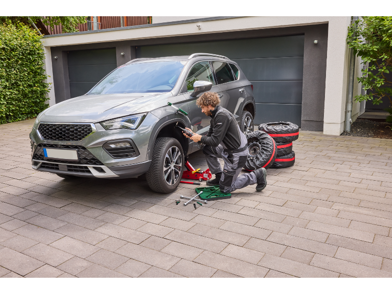 Homme changeant les pneus de voiture, utilisant un cric et une clé à chocs électrique.
