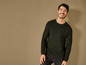 Un homme portant un pull vert et un jean.