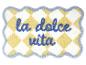 Tapis de bain à carreaux jaunes et blancs avec texte bleu « la dolce vita ».
