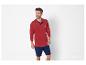 Un homme porte un polo The Sailor à manches longues rouge avec un short bleu.