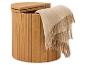 Panier à linge rond en bois clair avec couvercle ouvert et plaid beige en laine