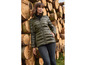 Une femme porte une veste d'hiver verte avec une ceinture devant une pile de bois.