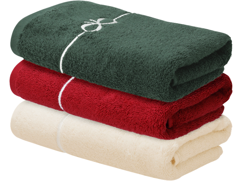 Trois serviettes pliées : verte avec un nœud, rouge et crème.