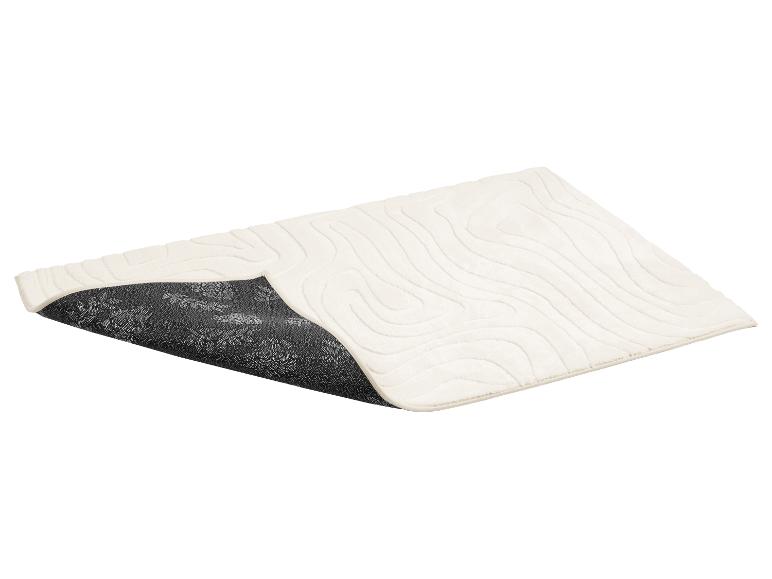 Tapis de bain crème avec motif de vagues et dessous antidérapant à motif floral.