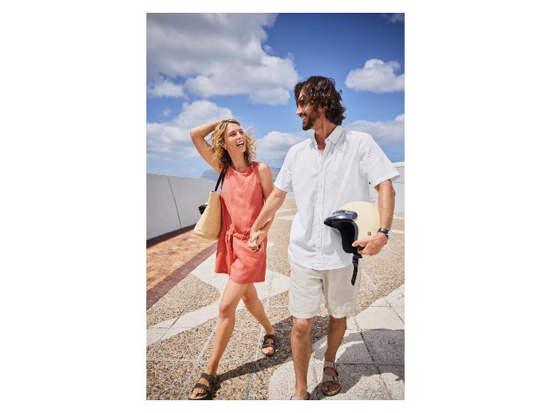 Couple heureux marchant, elle en robe et lui en chemise, casque de moto à la main.