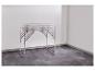 Table pliante en aluminium avec pieds réglables dans une pièce blanche au sol sombre.