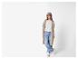 Femme en casquette, gilet long, jean et baskets