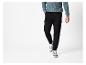 Homme en pull bleu et pantalon cargo noir avec des baskets blanches.