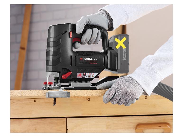 Mains gantées utilisant une scie sauteuse sans fil pour couper du bois.