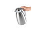 Une main tient une carafe isotherme en argent.