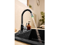 Robinet de cuisine noir avec lumière LED verte et eau courante dans un évier noir.
