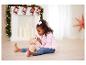 Une petite fille joue avec un chiot en peluche devant la cheminée à Noël.