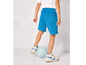 Un garçon portant un short bleu, des baskets blanches et un ballon de football.