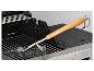 Brosse de nettoyage de barbecue posée sur la grille d'un barbecue à gaz.