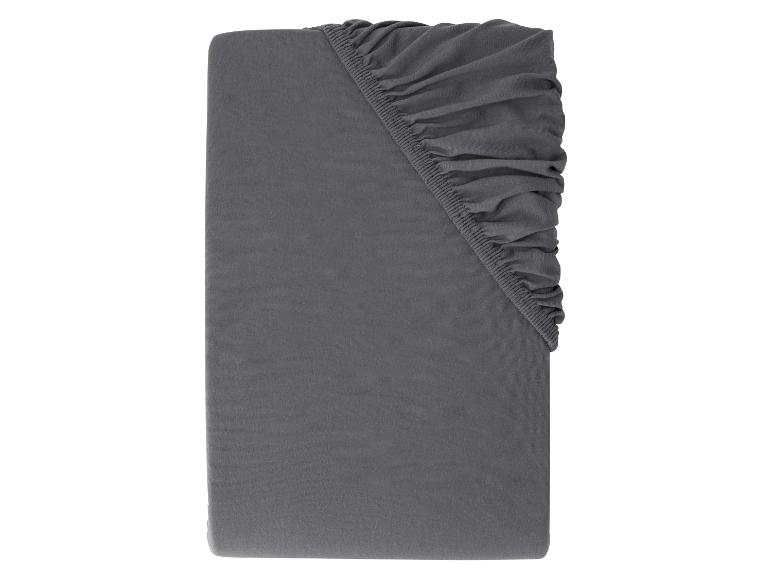 Drap-housse gris foncé plié sur fond blanc.