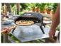 Four à pizza extérieur avec pizza sur pelle, cuite lors d'une fête de jardin.