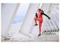 Femme en tenue de sport, gilet rose et leggings, sautant sur un pont blanc moderne.
