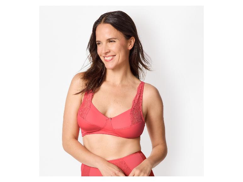 Femme en soutien-gorge et culotte en dentelle rouge, souriante et regardant sur le côté.