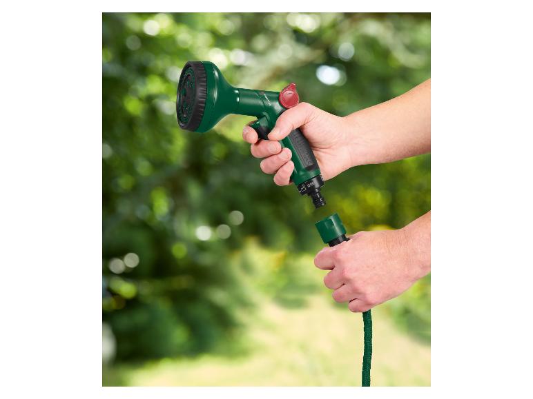 Mains connectant une buse de tuyau d'arrosage verte à un tuyau vert.