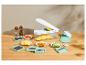 Mandoline à légumes avec divers accessoires et légumes coupés sur une table en bois.