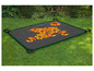 Un tapis de jardin gris foncé avec une bordure verte sur l'herbe, avec des feuilles d'automne dessus.