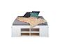 Lit blanc avec matelas gris, oreillers et couverture beige.