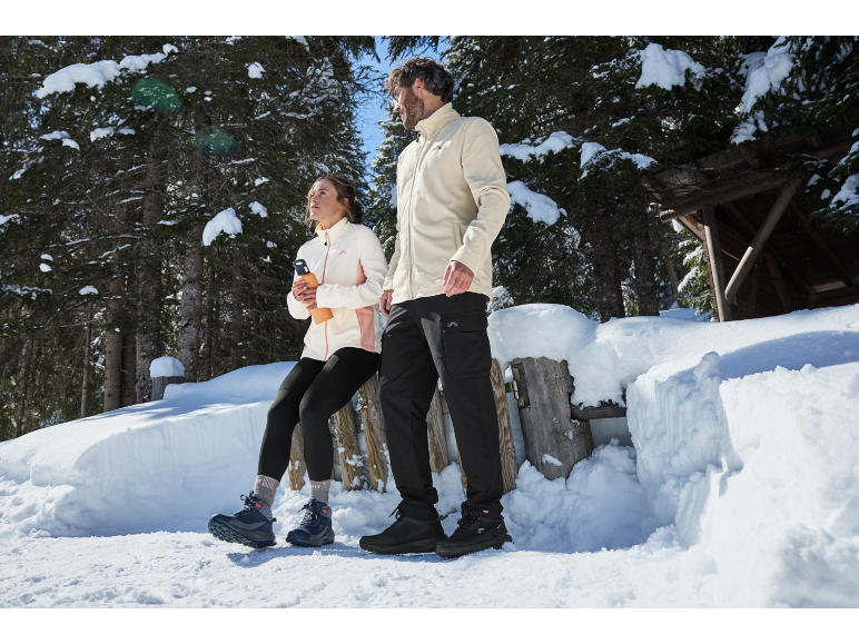 Homme et femme en vêtements et chaussures d'hiver dans une forêt enneigée.