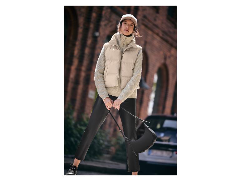 Femme avec un gilet beige, un pull en maille et un pantalon en cuir.