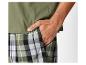 Un homme porte un t-shirt vert et un pantalon à carreaux.