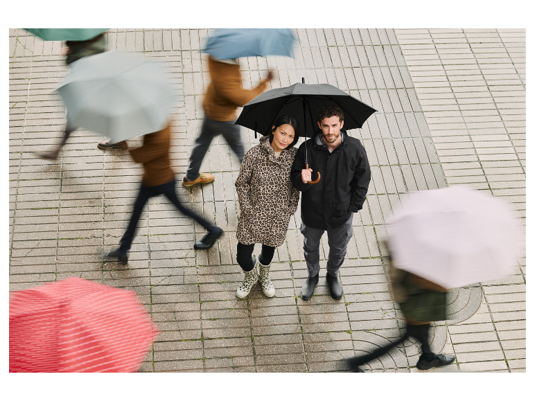 Un couple se tient sous un parapluie dans une rue pluvieuse.