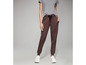 Une femme portant un pantalon de survêtement marron avec un cordon et des baskets blanches.