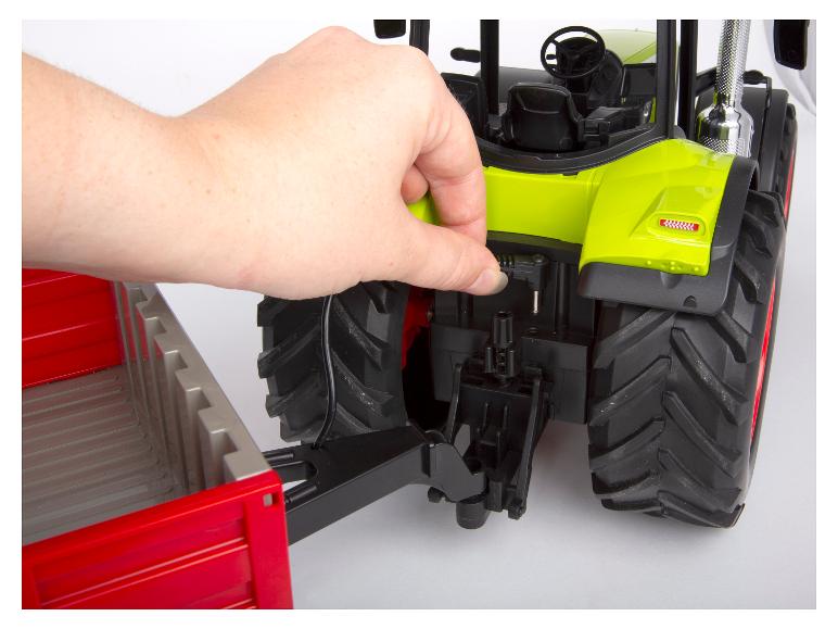 Une remorque est connectée manuellement à un tracteur Bruder radiocommandé.