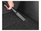 Une main utilise un embout d'aspirateur noir pour nettoyer une voiture.