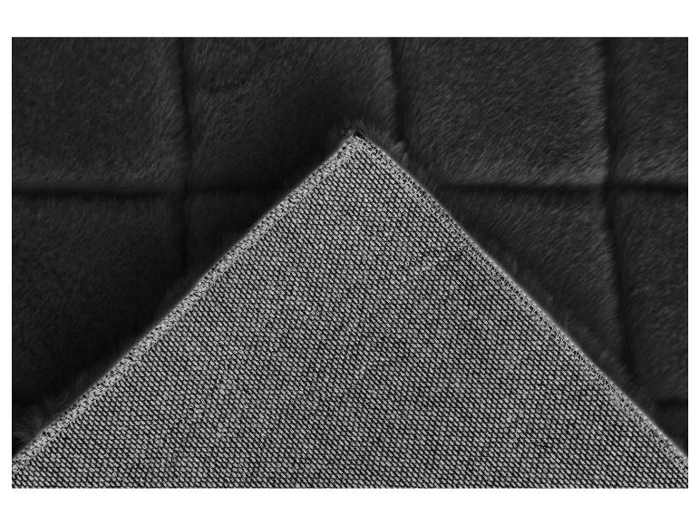 Un tapis noir en fausse fourrure avec un dos antidérapant gris.