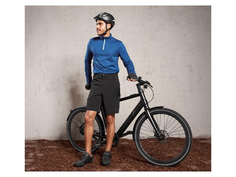 Un homme avec un casque et des chaussures de vélo est à côté d'un vélo noir.