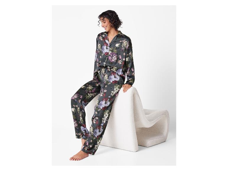 Femme souriante en pyjama de satin à imprimé floral, assise sur une chaise blanche.