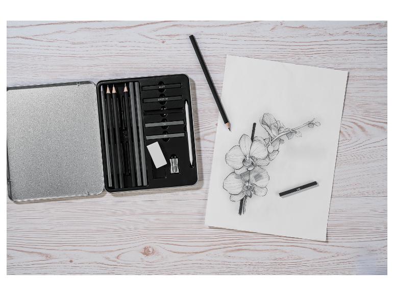 Kit de croquis avec crayons fusain et un croquis d'orchidée sur une table en bois.