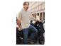 Homme en t-shirt beige et jean bleu s'appuyant sur un scooter.